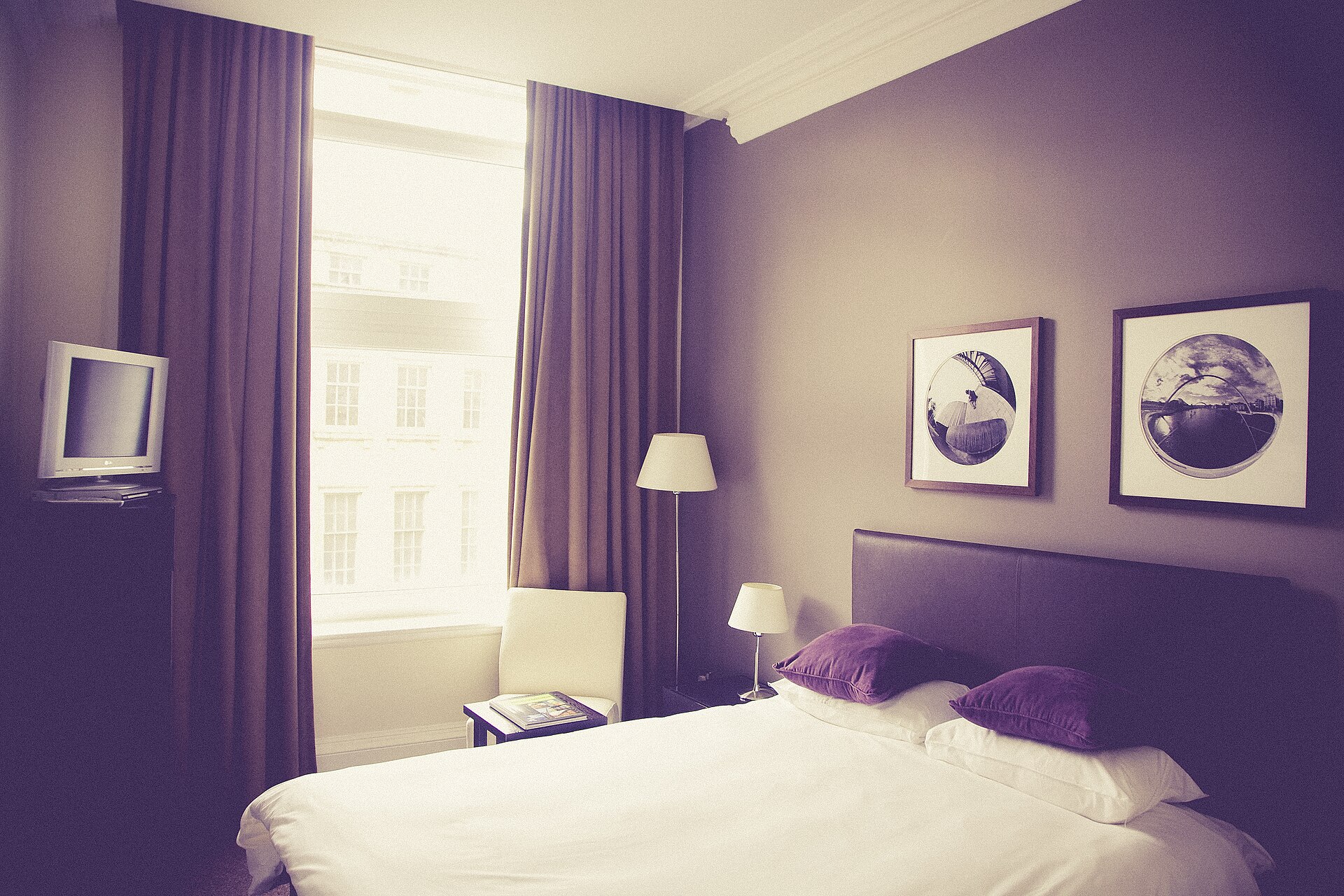 Calm hotel bedroom with daylight through large windows