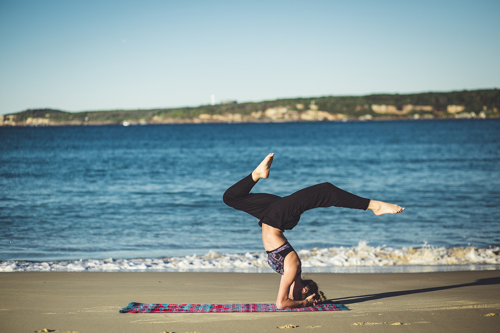 Person practising yoga beside the ocean