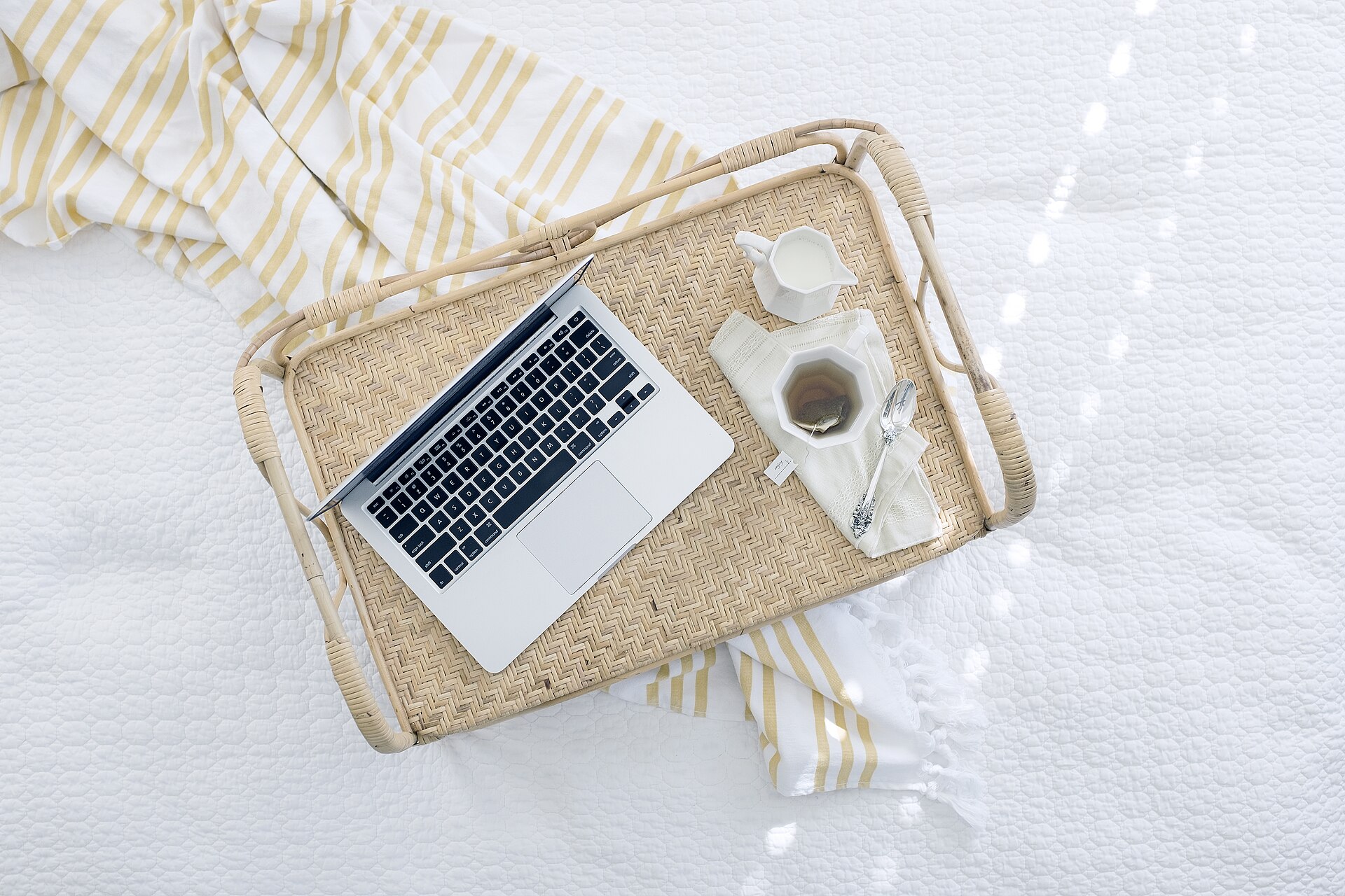 Laptop and drink arranged on a wicker tray for a quiet reset